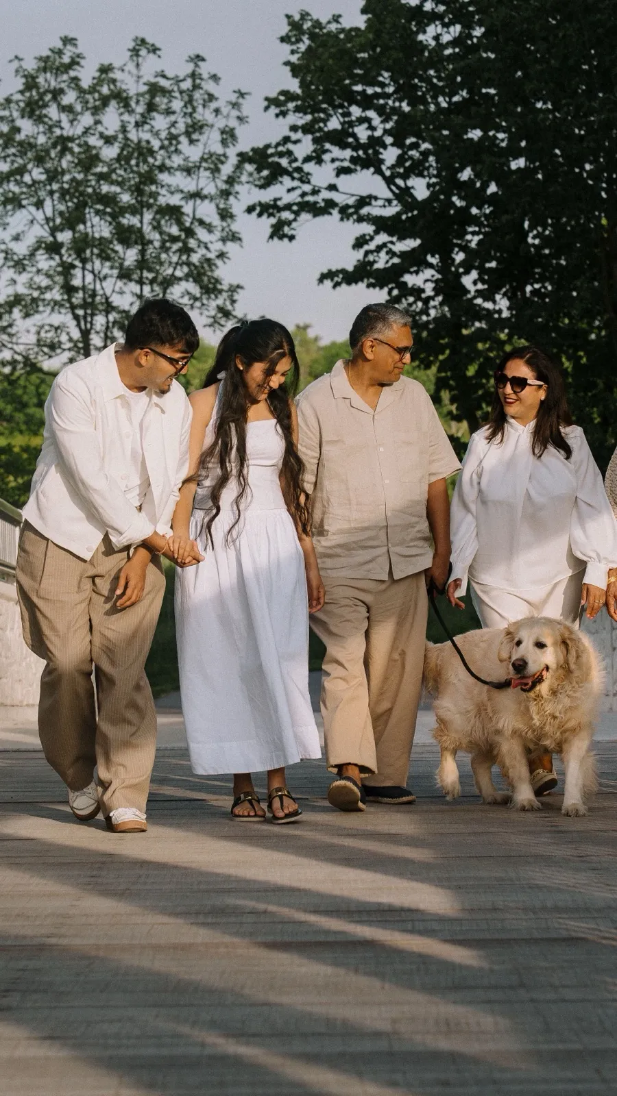 Dev walking on a footbridge with his family and their dog at golden hour