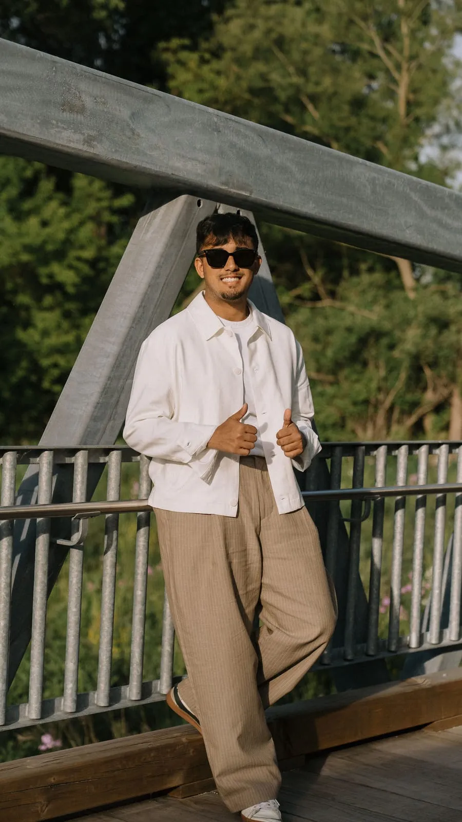 Dev leaning on a footbridge railing in the evening sun