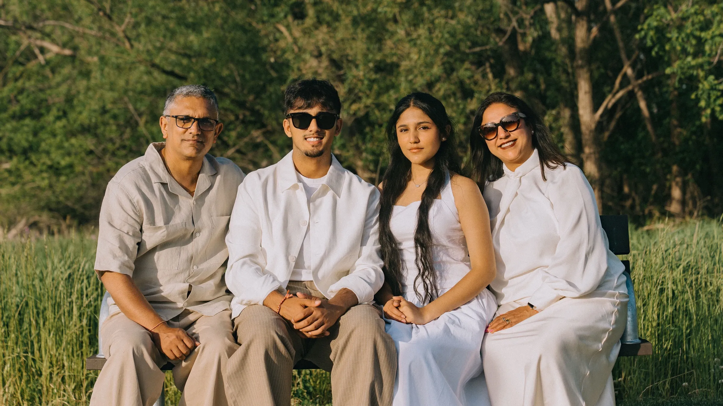 Dev Vashi with his father, mother and sister on a bench in a field at golden hour
