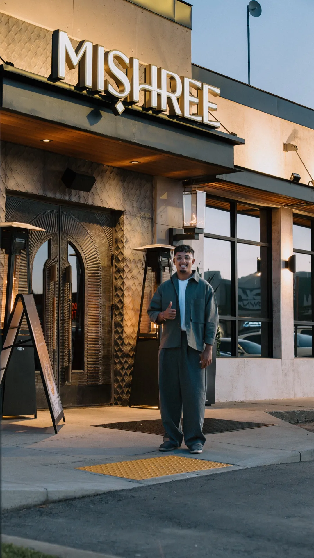 Dev giving a thumbs up in front of the Mishree restaurant in Ward 11 at golden hour