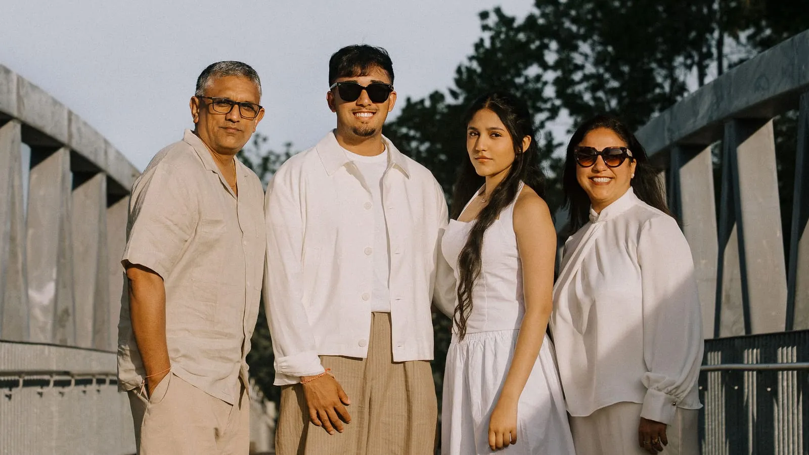 Dev with his father, sister, and mother on a footbridge in the evening sun